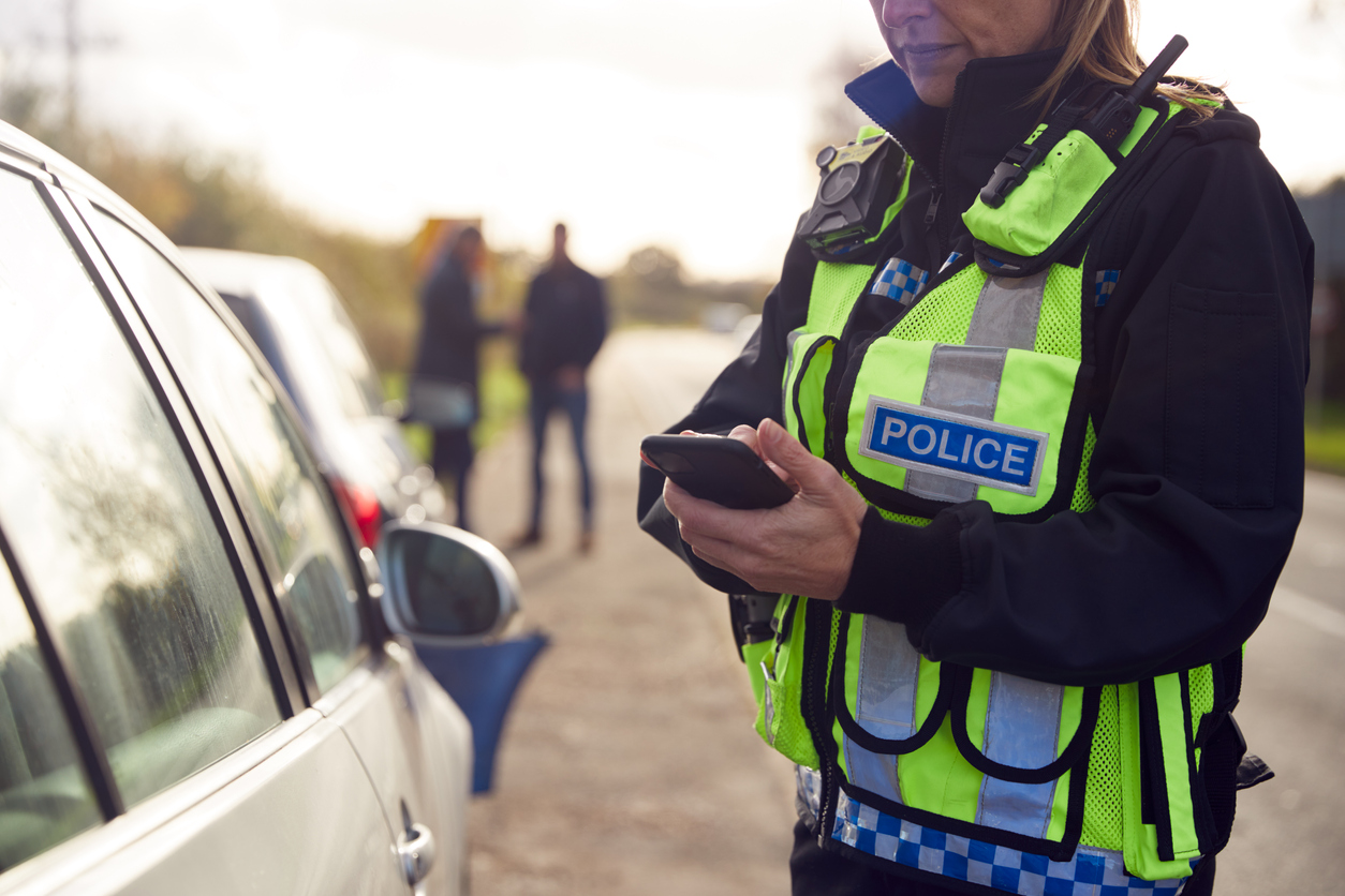 Police officer using a cell phone while at a crime scene.